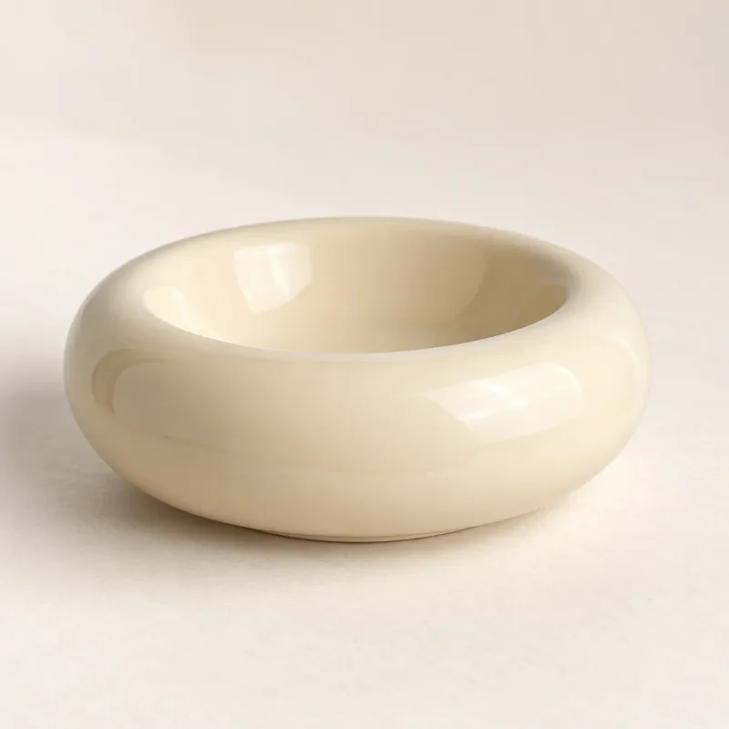 Empty cream ceramic Ring Bowl on a pale tabletop, showing the rounded ring rim and shallow basin.