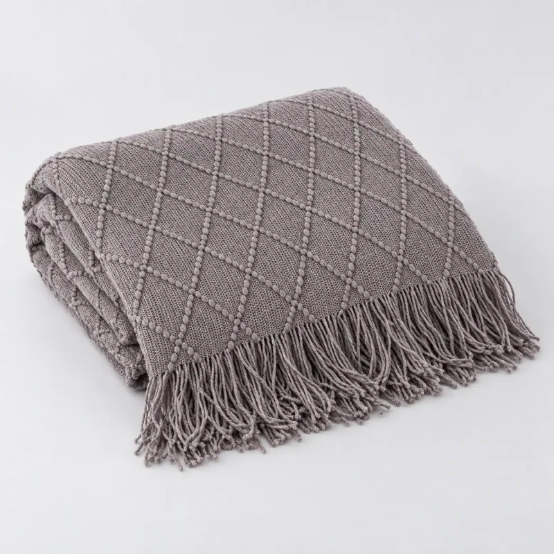 Folded gray throw showing the diamond knit and fringe