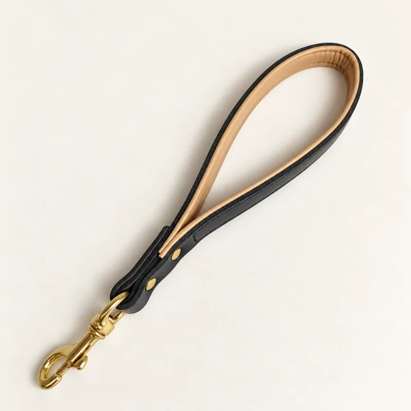 Short black leather loop lead with tan lining, two gold rivets and one gold swivel clasp.