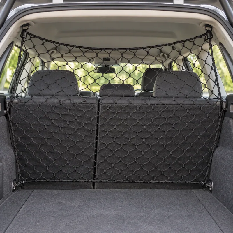 Black mesh divider installed behind upright rear seats in a parked car, with four corner hooks