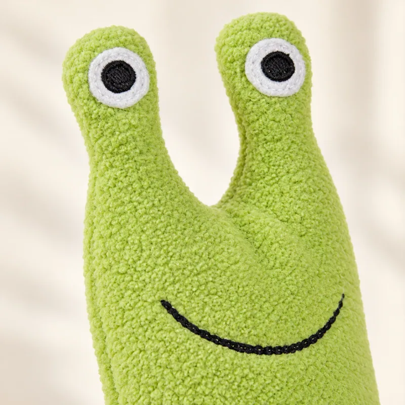 Close-up of the snail toy’s stitched eyes and smile and textured green fleece